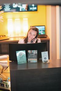 a woman talking on a cell phone at a desk at The Originals Boutique, Hôtel de la Paix, Brest in Brest