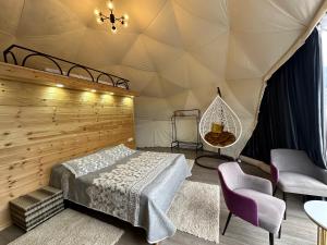 a bedroom in a tent with a bed and chairs at Asman Glamping in Karakol