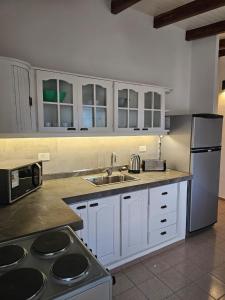 a kitchen with white cabinets and a sink and a refrigerator at Casa Montana in Potrero de Garay