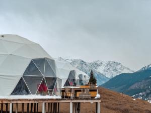 two domed tents on top of a hill with mountains at Asman Glamping in Karakol