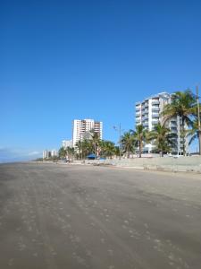 an empty beach with palm trees and buildings at Apartamento Estrela da Praia V19 in Mongaguá