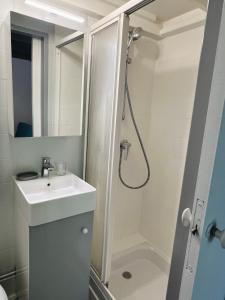 a white bathroom with a shower and a sink at Studio Georges 1er in Aix-les-Bains