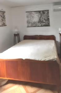 a bed with a wooden frame in a room at Maison charmante à Sainte-Anne avec climatisation - 70 m² in Sainte-Anne
