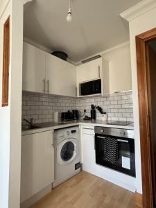 a kitchen with a washer and dryer in it at Stylish & compact city center studio apartment 7a in Norwich +3 photos