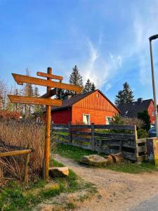 ein Holzschild vor einer roten Scheune in der Unterkunft HIRSCH Gretel Ferienhaus - Garten mit Grill - Wald in Altenau