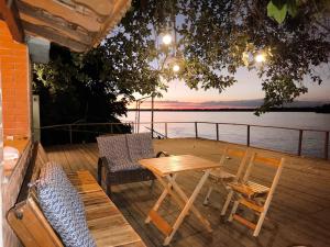 a table and chairs on a deck with a view of the water at Pousada Água Doce - Porto Eucalipto in Pôrto São José