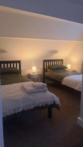 ein Schlafzimmer mit zwei Betten und zwei Tischen mit Lampen in der Unterkunft Charming Four Person Malthouse Apartment in Much Wenlock