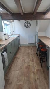 eine Küche mit Holzböden und einer Uhr an der Wand in der Unterkunft Charming Four Person Malthouse Apartment in Much Wenlock