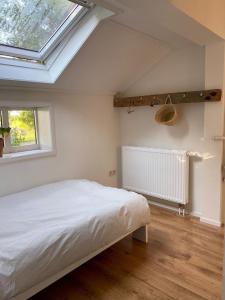 a bedroom with a white bed and a window at Boerderijhuisje 22 - Landelijk logeren bij Sneek in Loënga