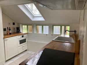 a kitchen with a sink and a kitchen with a skylight at Boerderijhuisje 22 - Landelijk logeren bij Sneek in Loënga