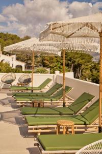 a row of lounge chairs and umbrellas on a patio at Casa El Sueño in Jávea