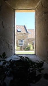 a window with a view of a house seen through it at St Hildas Complex in Hinderwell