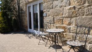 a table and two chairs next to a stone wall at St Hildas Complex in Hinderwell