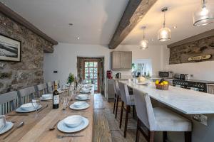 a dining room with a long table and a kitchen at Ty Mawr Llanfair in Llanfair