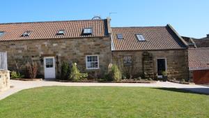 an old stone house with a lawn in front of it at St Hildas Complex in Hinderwell