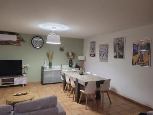 a living room with a table and chairs and a tv at Maison individuelle 90m2 avec véranda et piscine in Roquemaure