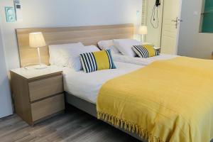 a bedroom with two beds and a yellow blanket at Les Gîtes du Domaine de Ludeye in Listrac-Médoc