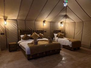 a bedroom with two beds in a tent at Milagro Luxury camp & AC in Merzouga