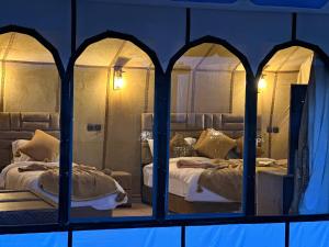 a bedroom with two beds and a mirror at Milagro Luxury camp & AC in Merzouga