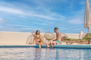a man and a woman sitting on the edge of a swimming pool at Casa El Sueño in Jávea