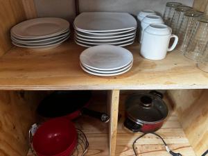 a shelf with plates and cups and dishes on it at proteas departamento interior in Pichilemu