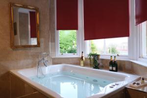 a large bath tub in a bathroom with two windows at St Hildas Complex in Hinderwell