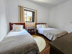 2 camas en una habitación con mesa y ventana en Casa perto do Parque dos Saltos - Brotas - Casa 3, en Brotas