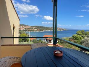 a blue table on a balcony with a view of the water at The Yellow Houses in Agios Nikolaos
