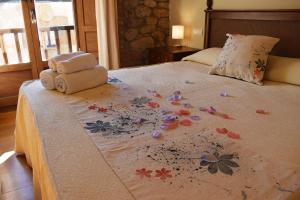 a bed with a blanket with flowers on it at Hotel Rural CHOUSA VERDE in Vegacervera