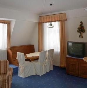 Habitación con mesa, sillas y TV. en Apartment Grattschlössl, en Sankt Johann in Tirol