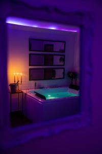 a dark room with a tub with a purple light at La suite BLR in Villemandeur +5 photos