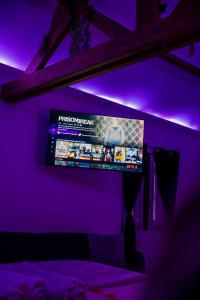 a tv in a room with purple lights at La suite BLR in Villemandeur