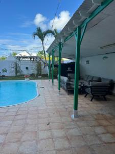 a swimming pool with chairs and a pavilion next to at Location tropical in Sainte-Anne