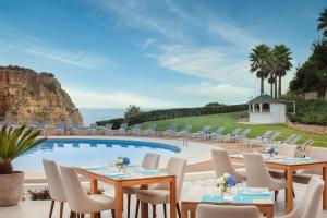 a restaurant with tables and chairs next to a pool at Tivoli Carvoeiro in Carvoeiro