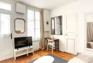 ein Wohnzimmer mit einem TV und einem Tisch mit einem Stuhl in der Unterkunft Le Chat Botté - Versailles in Versailles