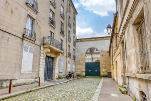 eine Gasse zwischen zwei Gebäuden mit einer grünen Tür in der Unterkunft Le Chat Botté - Versailles in Versailles