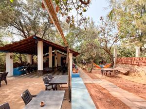 a picnic shelter with tables and chairs in a park at Aangan by Gokarma Living in Gokarna