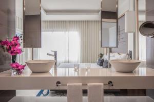 a bathroom with two sinks and flowers on a counter at Tivoli Carvoeiro in Carvoeiro