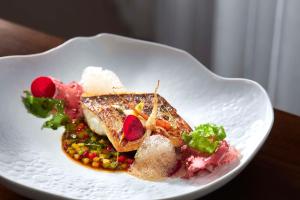 a white plate with a dish of food on a table at Tivoli Carvoeiro in Carvoeiro