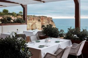 a restaurant with tables and chairs with a view of the ocean at Tivoli Carvoeiro in Carvoeiro