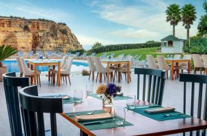 a restaurant with tables and chairs next to a pool at Tivoli Carvoeiro in Carvoeiro