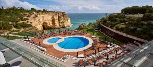 a view of a pool with the ocean in the background at Tivoli Carvoeiro in Carvoeiro