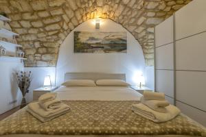 ein Schlafzimmer mit einem Bett mit einer Steinwand in der Unterkunft La casetta di Pietra in Sassari