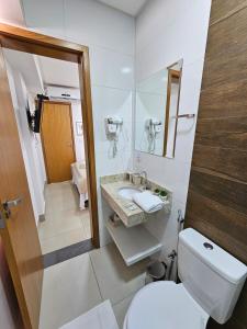 a white bathroom with a toilet and a sink at Lindissimo Flat 101 a uma esquina Flamboyant Shop in Goiânia