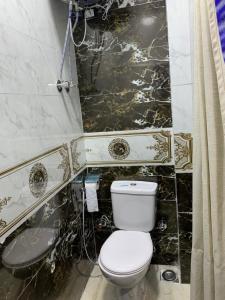 baño con aseo y pared de mármol blanco y negro. en Comfort Suite Near Triumph Luxury Hotel, en El Cairo