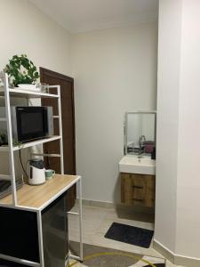 baño con lavabo y escritorio con TV en Comfort Suite Near Triumph Luxury Hotel, en El Cairo