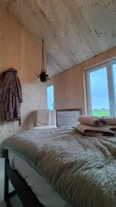 a bedroom with a large bed with two chairs and windows at Boerenerf Lodge - Erf 1 in Kampen