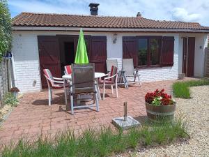 a patio with a table with chairs and a green umbrella at Zeepolder Ii 70 in De Haan