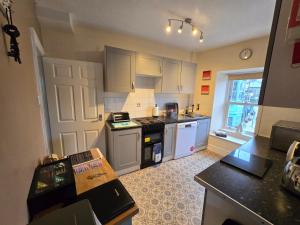 a kitchen with white cabinets and an open door at Luxury 4 Bedroom Seaside Apartment - Glan Y Werydd House in Barmouth