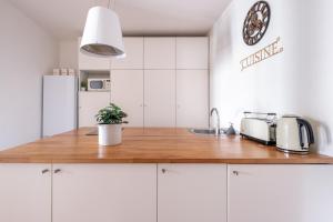 a kitchen with white cabinets and a wooden counter top at Havre de Raffinement à Levallois-Perret in Levallois-Perret